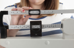 A woman adjusts a physician scale.