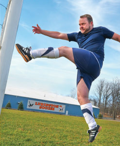Brad Reed kicks a soccer ball on a soccer field.