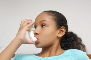 A young girl uses an asthma inhaler.