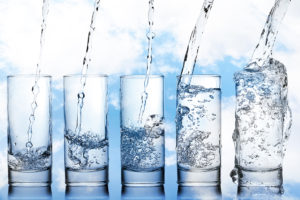 Water is shown being poured into multiple glasses.