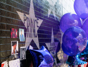 A shrine with balloons and pictures of Prince is shown.