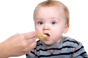 A toddler is fed with a yellow spoon.