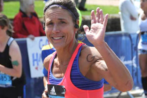 Gina Otterbein waves to the crowd during the Boston Marathon.