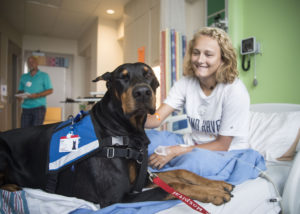 Grand Haven resident Sara Bergman, 17, pets Bullet, a 6-year-old Doberman Pinscher, as he lays in her bed during the West Michigan Therapy Dogs visit at Spectrum Health Helen DeVos Children's Hospital.