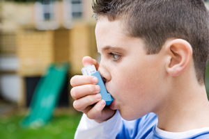 A young boy uses his asthma inhaler.