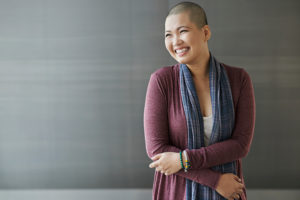A woman with no hair poses for a photo and smiles big.