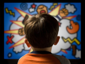 A young boy stares at a screen with violent images.