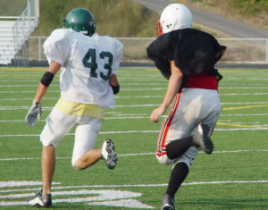 Two young football players run on a football field.