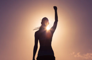 A woman raises her fist in the air as she basks in the sun.