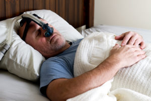 A man wears a sleep apnea mask while sleeping.