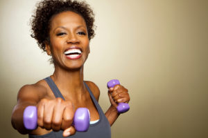 A woman exercises her arms with purple dumbbells.
