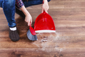 A person sweeps dust off a wood floor.