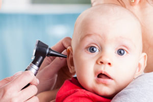 A baby boy gets his ear looked at by a medical professional.