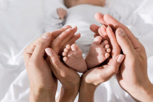A mother and father hold their newborn baby's feet.