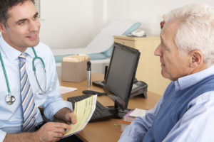 An elderly man talks to his doctor at his appointment.