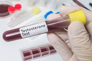 A person wears a medical glove and holds a test tube labeled, "Testosterone Test."
