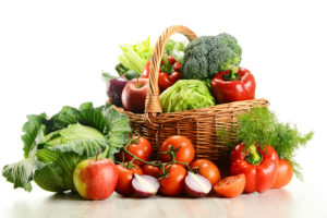 A basket is overflown with vegetables and fruit.