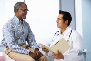 A man talks with his doctor at a regular screening.