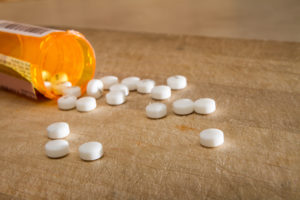 A prescription bottle lies on a table and spills out pills.