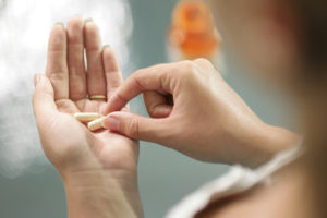 A woman places two calcium supplements into her hand.