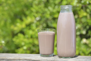 A full bottle and glass of chocolate milk sit next to each other.