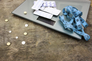 A scale is shown with pills and measuring tape.