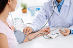 A woman has her blood pressure measured by her doctor.