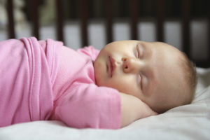 A baby girl is asleep in her crib.