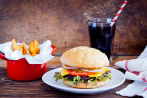 A burger, fries and a soda pop are shown.