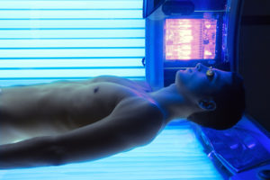 A man lies in a tanning booth.