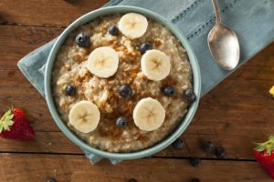 A bowl of oatmeal with blueberries, bananas and brown sugar is shown.