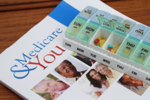 A weekly pill container is shown on top of a brochure that says, "Medicare & You."