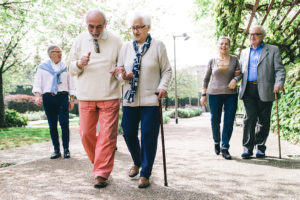 A group of elderly adults walk outside together.