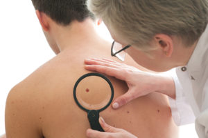 A medical professional looks at a man's back with a medical magnifying glass.