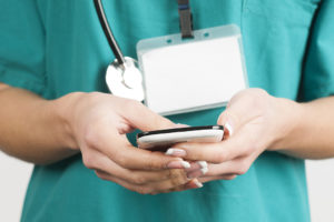 A medical professional holds a smartphone.