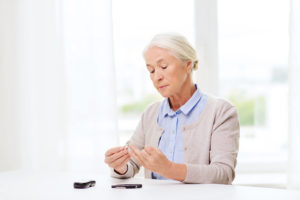 An elderly woman looks at her glucose monitoring system.