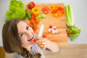 A woman, who is a vegetarian, eats a tomato.
