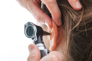 A doctor uses an octoscope to look into a woman's ear.