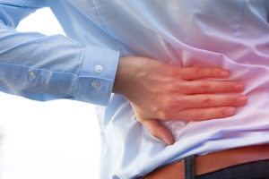 A person holds their back. They appear to have back pain.