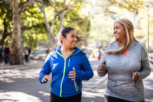 Two women run outside together.