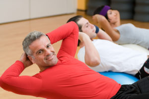 Three people appear to be exercising together and doing ab exercises.