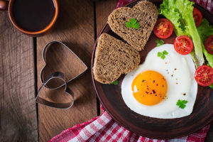 A plate with heart-shaped eggs and toast is in focus.