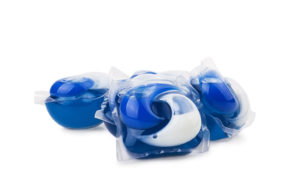 Blue-and-white liquid laundry detergent pods are in focus.