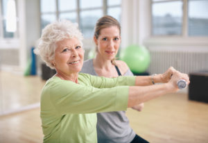 An elderly woman works out with a fitness instructor.
