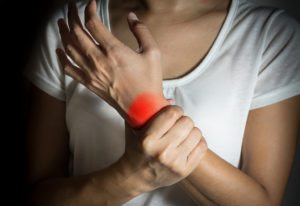 A woman holds her wrist.