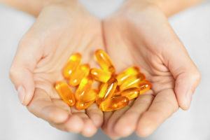 A person holds fish oil pills in their hands.