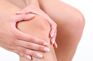 A person holds their knee cap.
