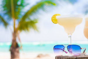 A Margarita is in focus. The beach is in the background.