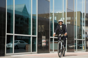 A person rides their bike around a city. He appears to be riding his bike to work, as he is dressed in business apparel.