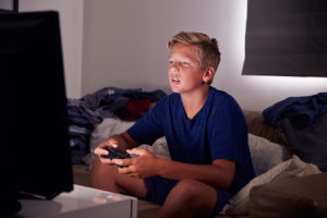 A young boy plays video games on a couch.
